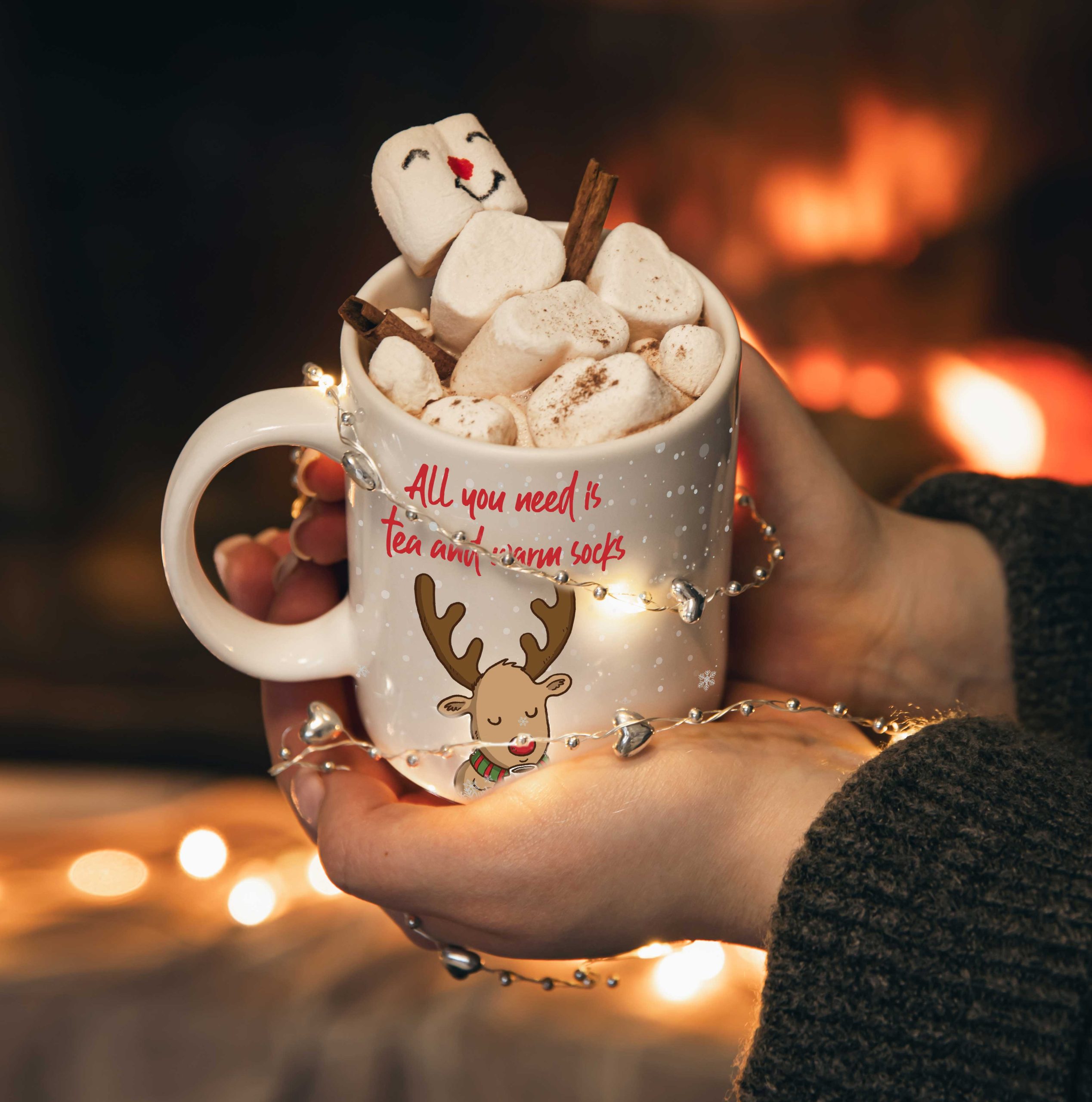 Novogodišnja šolja sa irvasom, puna marshmallowa i cimeta, ispred toplog kamina.